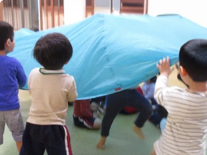 園児が青いブルーシートを敷いている画像